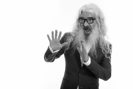 Studio shot of senior bearded businessman looking scared