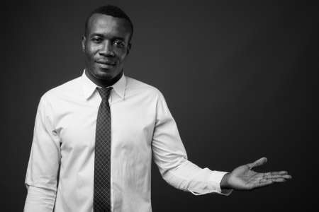 Studio shot of young African businessman against gray backgroundの写真素材