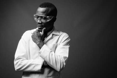 Studio shot of young African man doctor against gray backgroundの写真素材