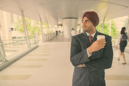 Young handsome Indian Sikh businessman wearing turban while exploring the cityの写真素材