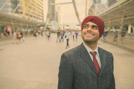 Young handsome Indian Sikh businessman wearing turban while exploring the cityの写真素材