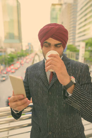 Young handsome Indian Sikh businessman wearing turban while exploring the cityの写真素材