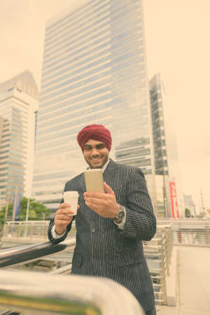 Young handsome Indian Sikh businessman wearing turban while exploring the cityの写真素材