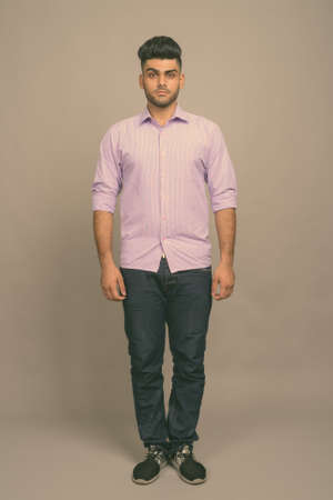 Young handsome Indian businessman against gray backgroundの写真素材