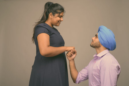 Young Indian couple together and in love against gray background