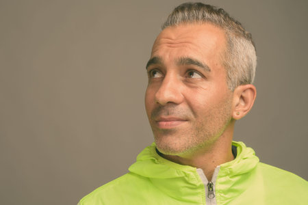 Handsome Persian man with gray hair against gray background