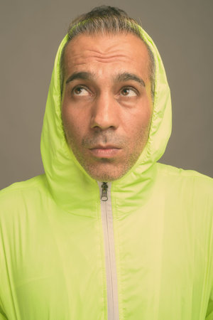 Handsome Persian man with gray hair against gray background
