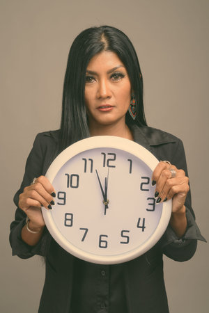 Mature beautiful Asian businesswoman against gray background