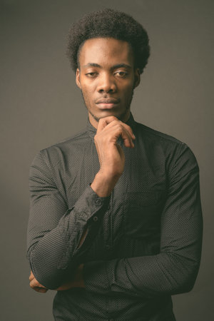 Young handsome African businessman against gray background