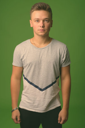 Studio shot of young handsome man against green background