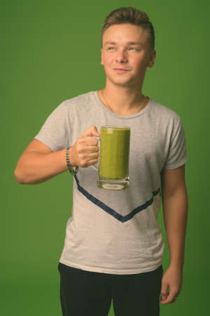 Studio shot of young handsome man against green backgroundの写真素材