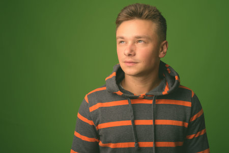 Studio shot of young handsome man against green backgroundの写真素材