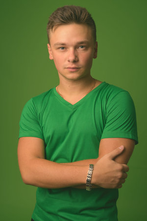 Studio shot of young handsome man against green background