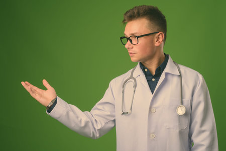 Young handsome man doctor against green background