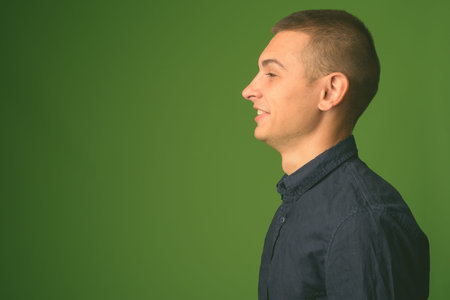 Studio shot of young handsome businessman against green background