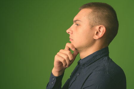 Studio shot of young handsome businessman against green background