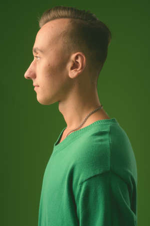 Studio shot of young handsome man against green backgroundの写真素材