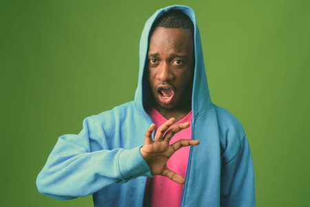 Studio shot of young African man against green backgroundの写真素材