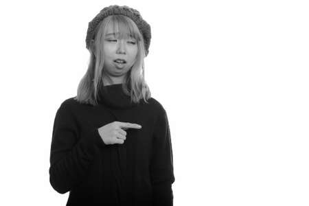 Young cute Asian woman looking upset and pointing finger at sideの写真素材