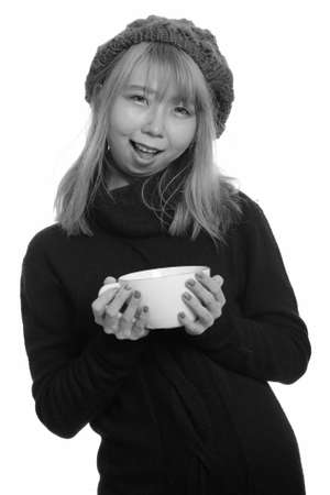 Young happy Asian woman smiling and holding coffee cupの写真素材