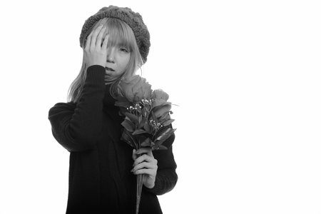 Young cute Asian woman holding roses looking stressed