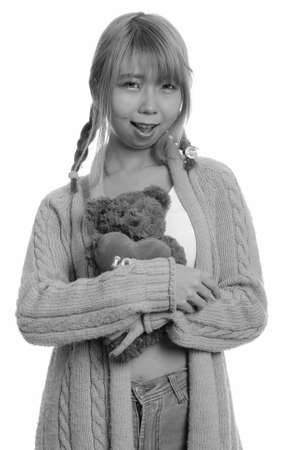 Young happy Asian woman smiling and hugging teddy bear with heart and love signの写真素材