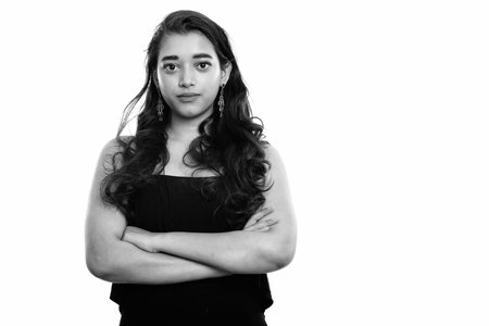 Studio shot of young beautiful Indian woman with arms crossedの写真素材