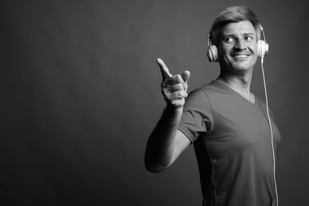 Man with blond hair listening to music against gray background
