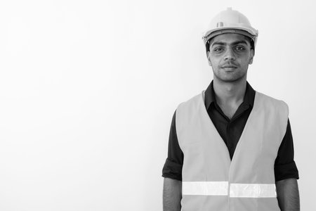 Young Indian man construction worker against white background