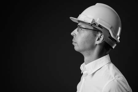 Portrait of businessman wearing hardhat against gray backgroundの写真素材