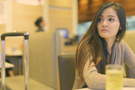 Young beautiful Asian woman sitting inside the restaurant