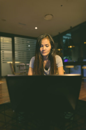 Young beautiful Asian woman using laptop in the living room