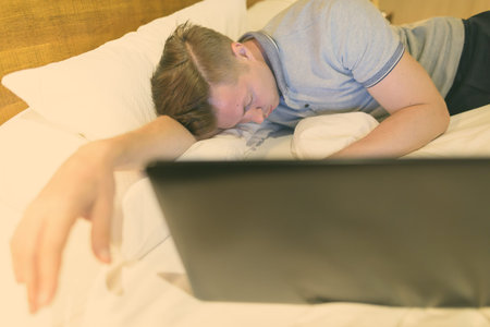 Young handsome man using laptop while being comfortable in the bedroom