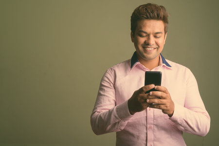 Indian businessman wearing pink shirt against colored background