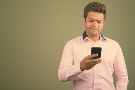 Indian businessman wearing pink shirt against colored background
