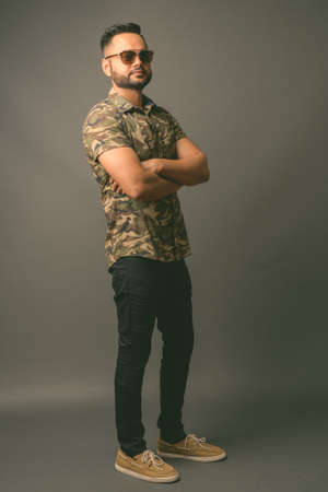 Young bearded Indian man against gray backgroundの写真素材