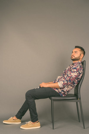 Young bearded Indian man against gray background
