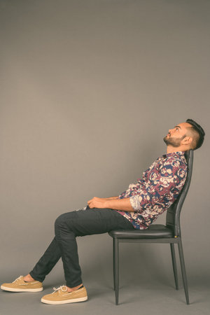 Young bearded Indian man against gray background