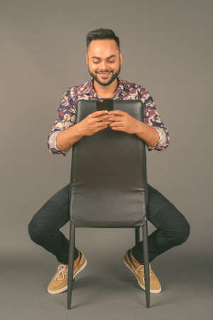 Young bearded Indian man against gray backgroundの写真素材