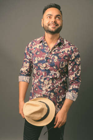 Young bearded Indian tourist man against gray backgroundの写真素材