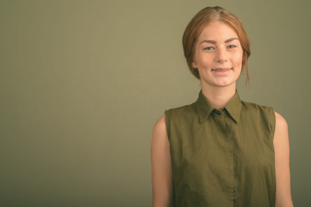 Young woman wearing green sleeveless top against colored background