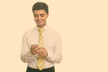 Young happy Persian businessman using mobile phoneの写真素材