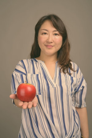 Mature beautiful Asian businesswoman against gray background