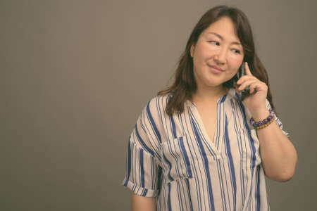 Mature beautiful Asian businesswoman against gray backgroundの写真素材
