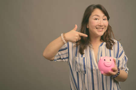Mature beautiful Asian businesswoman against gray backgroundの写真素材
