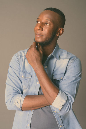 Young handsome African man with short hair against gray background