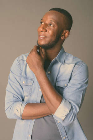 Young handsome African man with short hair against gray backgroundの写真素材