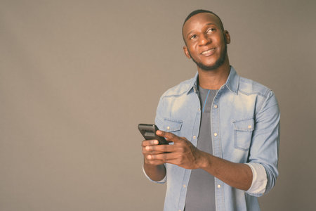 Young handsome African man with short hair against gray background