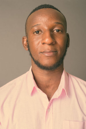 Young handsome African man with short hair against gray background