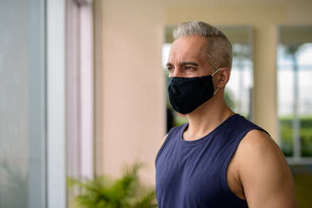 Mature Persian man with mask thinking while social distancing at the gymの写真素材